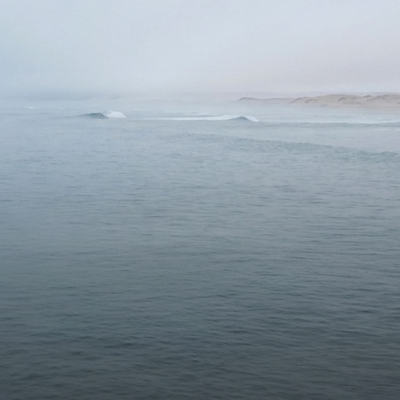 A calm ocean under heavy mist